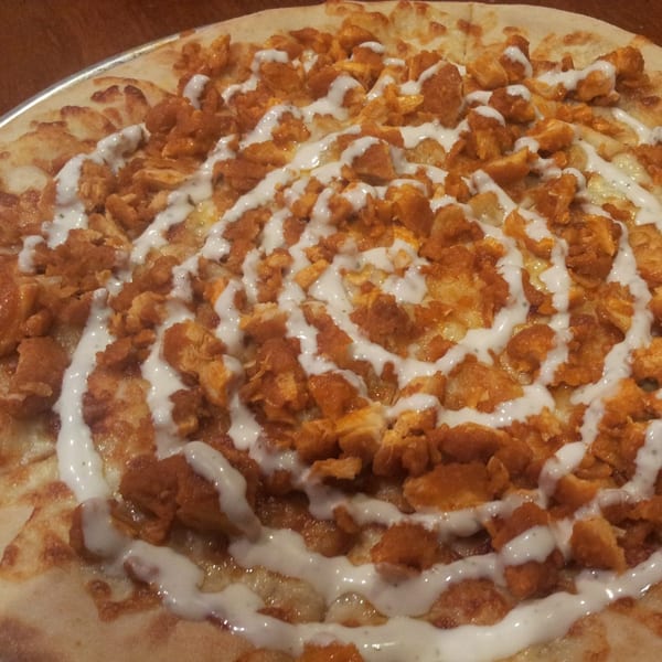 Buffalo chicken pizza from Town Pub, topped with ranch dressing in a spiral pattern.