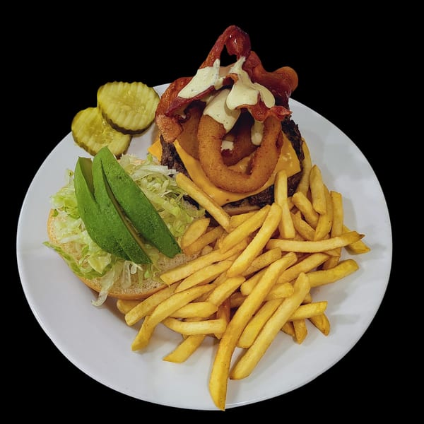 Town Pub's bacon cheeseburger with onion rings, avocado, lettuce, pickles, and fries on a white plate.