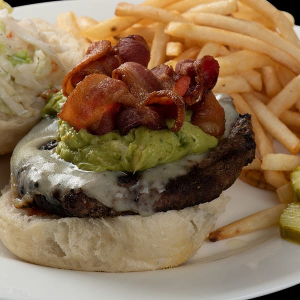 Town Pub's bacon cheeseburger with guacamole, fries, coleslaw, and pickles on a white plate.