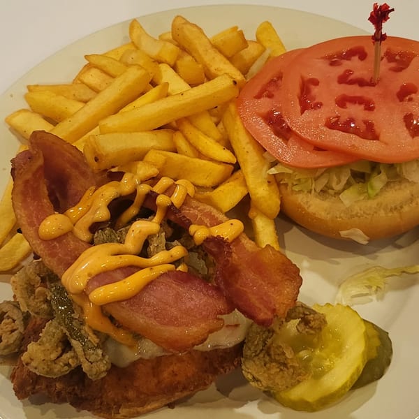 A bacon cheeseburger with fried pickles, special sauce, and a side of french fries.
