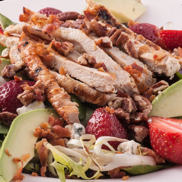 Close-up of a Town Pub salad with sliced chicken, strawberries, avocado, pecans, and bacon.