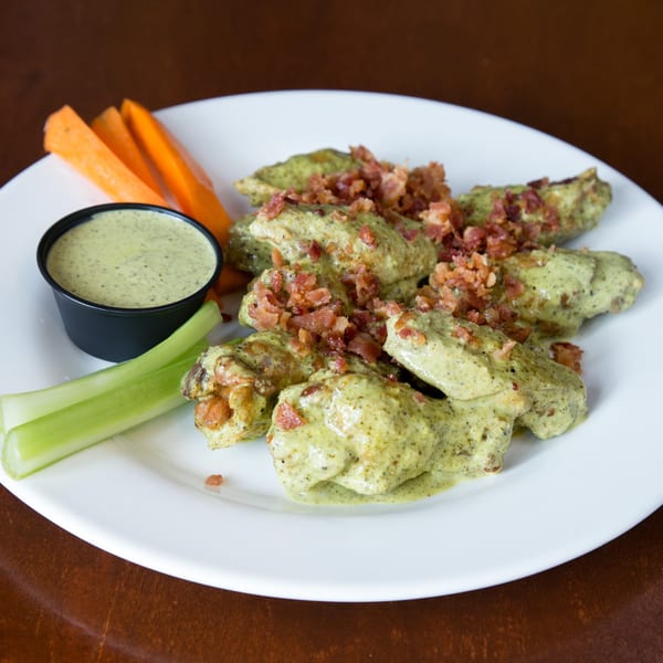 Town Pub's green-sauced chicken wings topped with bacon bits, served with celery, carrots, and dipping sauce.