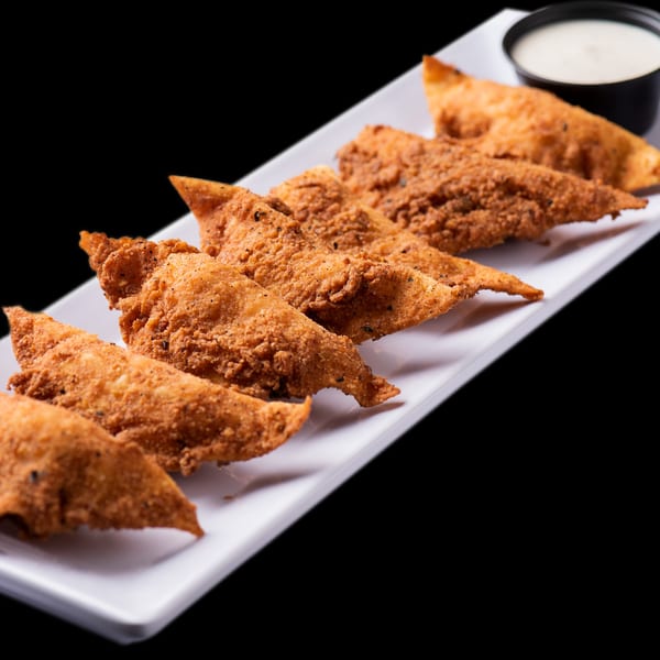 Crispy fried chicken tenders with a side of ranch dressing on a white rectangular plate.
