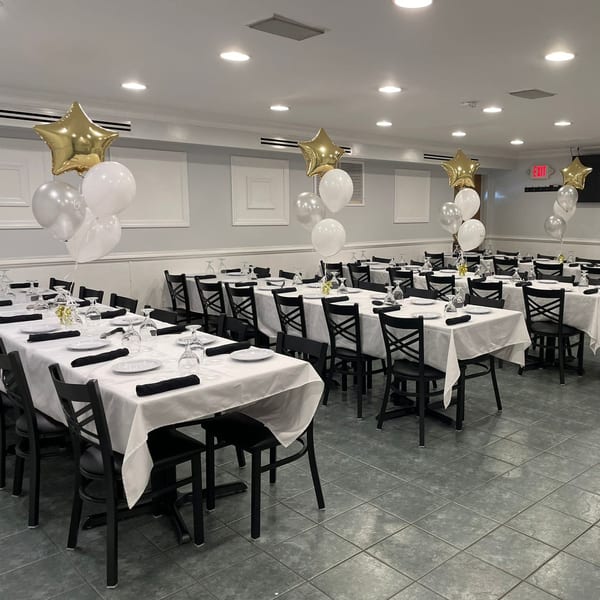 A Town Pub dining room set for a party with white tablecloths, black chairs, and star balloons.