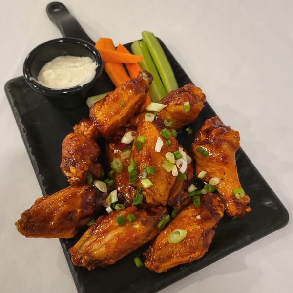 Town Pub's chicken wings, glazed with sauce and topped with green onions, served with ranch, carrots, and celery.