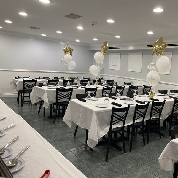 A dining room at Town Pub set with white tablecloths, black chairs, and celebratory balloons.