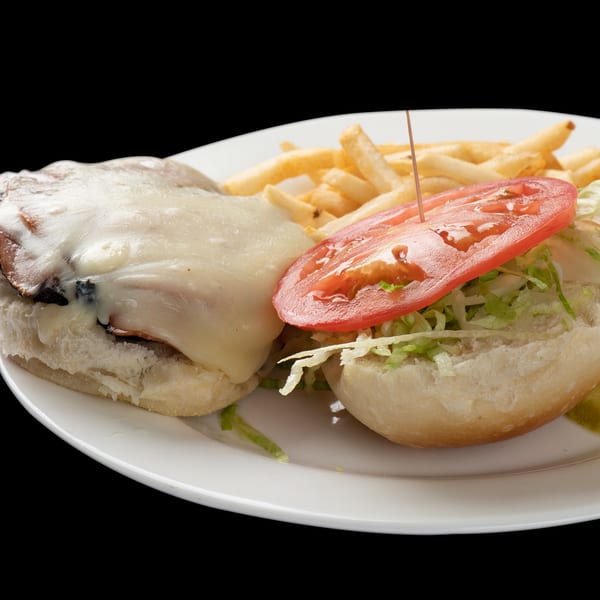 Mushroom Swiss burger with fries, lettuce, and tomato on a white plate at Town Pub.