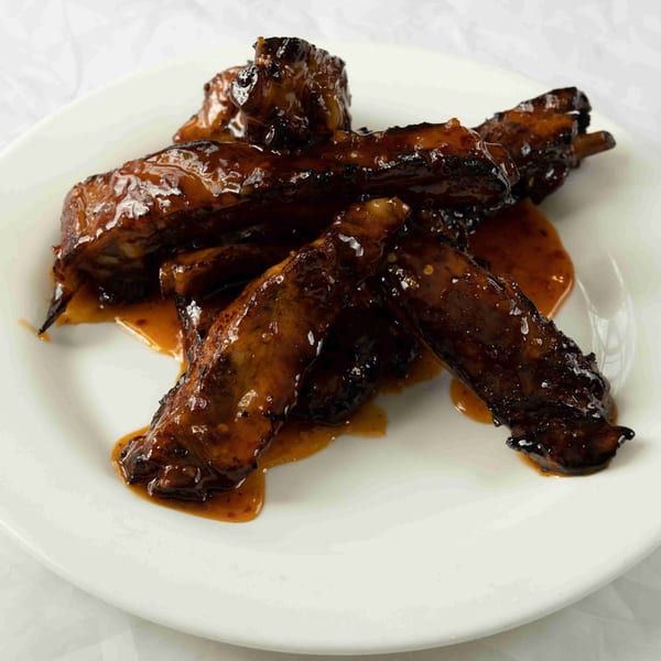 Glazed BBQ ribs, glistening with sauce, arranged on a white plate at Town Pub.