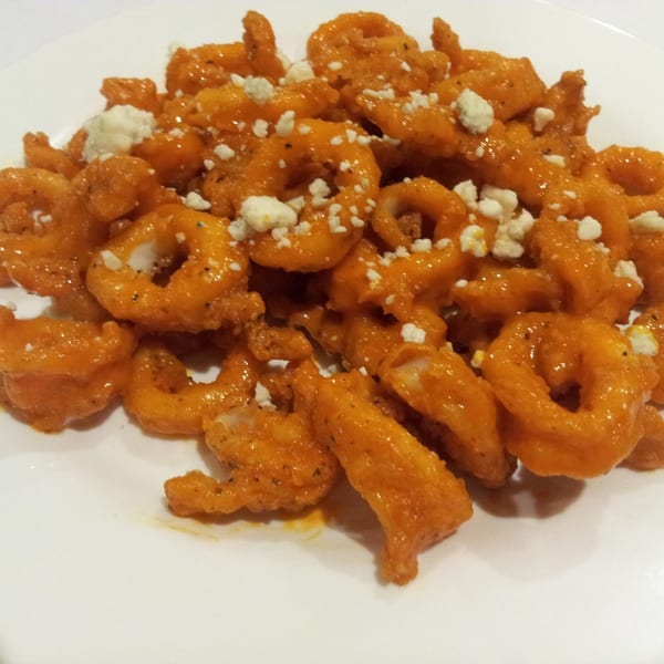 Buffalo shrimp appetizer with blue cheese crumbles on a white plate at Town Pub.